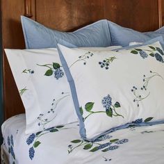 a bed with blue flowers and green leaves on the pillowcase, along with two pillows