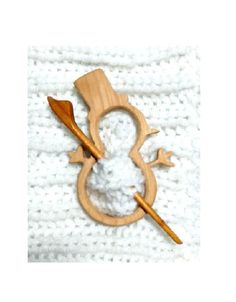 a crocheted white cloth with a wooden snowman ornament on it