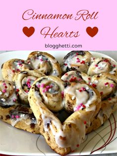 cinnamon roll hearts on a white plate with pink and red sprinkles in the middle