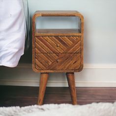 a wooden night stand sitting on top of a white rug