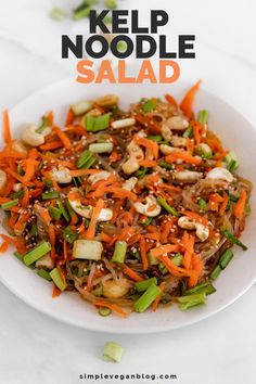 a white bowl filled with carrots, onions and sesame seed salad on top of a table