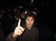 a young man pointing at the camera while standing in front of a group of people