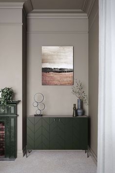 a living room with a fireplace and green cabinet in the corner next to a painting on the wall