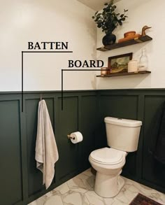 a white toilet sitting in a bathroom next to a towel rack and potted plant