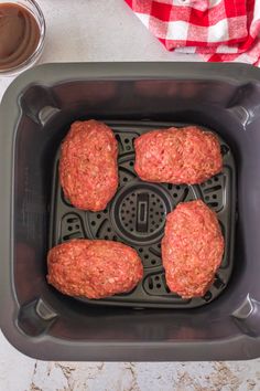 four hamburger patties in a deep fryer with ketchup on the side