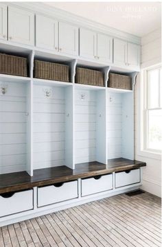 an empty room with several white shelves and baskets on the top, along with wood flooring