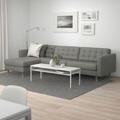 a living room with a gray couch and white coffee table in front of a window