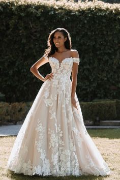 a woman standing in the grass wearing a wedding dress