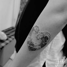 a black and white photo of a wave tattoo on the arm