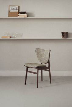 a chair sitting on top of a white floor next to a shelf filled with books