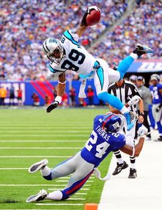 a football player jumping into the air to catch a ball in front of another player