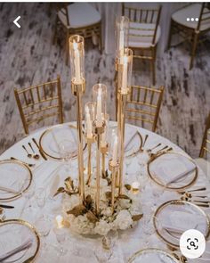 an image of a table setting with gold and white flowers on the centerpieces