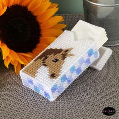 a cross stitch horse on a blue and white blanket next to a sunflower