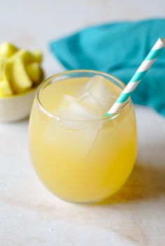 a glass filled with yellow liquid and topped with a blue striped straw