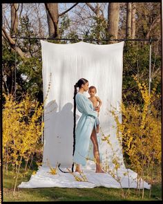 two women standing in front of a white backdrop with yellow flowers and trees behind them