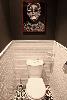 a white toilet sitting in a bathroom next to a painting