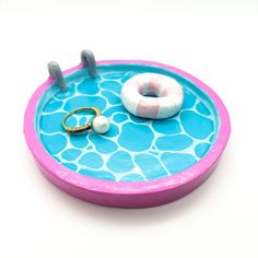 a pink and blue tray with two rings on it, sitting next to a donut