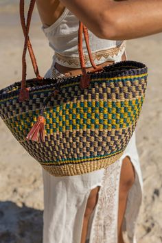 Our African Woven Basket is a versatile piece that adapts to your needs. This tote basket can be molded when wet and shaped to be round or narrow with a latch to close. With long leather handles, it's perfect for comfortable over-the-shoulder style.Measuring approximately 10-14 inches in width, 8-12 inches in height, and 6-8 inches in depth.Our exquisite African Artisan Baskets are a product of rich tradition, ethical sourcing, and sustainable craftsmanship. These unique baskets embody the spiri Blue Top Handle Straw Bag For Travel, Blue Top Handle Straw Bag For Everyday Use, Natural Color Basket-shaped Bucket Bag With Detachable Handle, Natural Basket-shaped Bucket Bag With Detachable Handle, Leather Bucket Beach Bag, Blue Bucket Bag With Braided Handles For Travel, Beach Shoulder Bag With Handle Drop, Daily Use Basket Shoulder Bag With Detachable Handle, Travel Bucket Bag With Detachable Handle In Basket Shape