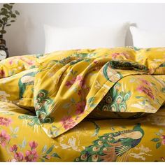 a bed covered in yellow and pink flowers with pillows on the headboard next to it