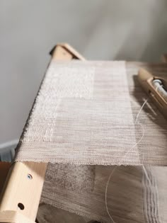 a close up of a piece of cloth on a table with a sewing machine in the background