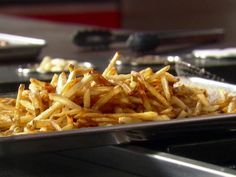 french fries are piled on top of each other in a metal tray, ready to be eaten