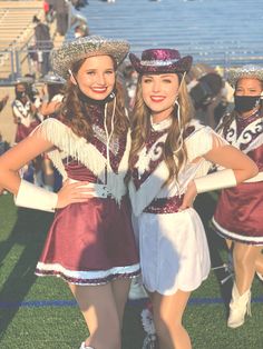 two young women dressed in cheerleader outfits posing for a photo on the sidelines