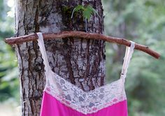 a pink and white dress hanging on a tree branch in front of a tree trunk