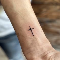 a woman's wrist with a small cross tattoo on the left side of her arm