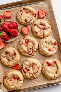 strawberry cookies and strawberries on a baking sheet