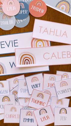 several different name tags and stickers on a wooden table with rainbows in the background