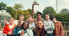 a group of people standing next to each other in front of a giraffe