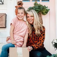 a mother and daughter are sitting on the front porch with their cardboard boxes in front of them