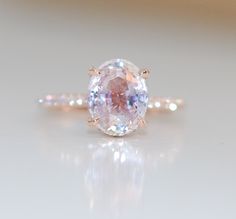 an oval shaped pink diamond ring on a white surface