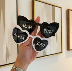 two heart shaped sunglasses are held up in front of a mirror with the names and date on them