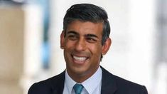 a man in a suit and tie smiles for the camera while wearing a white shirt and blue tie