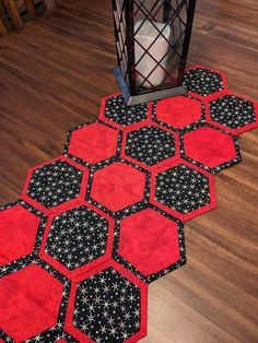 two red and black hexagonal rugs on the floor next to a lantern