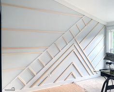 a room with a desk and chair next to a wall that has lines painted on it