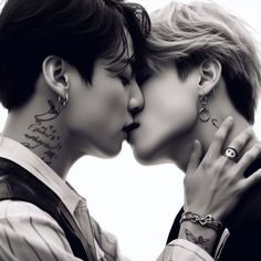 two people are kissing each other with tattoos on their faces and neck, both wearing matching rings