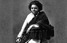 an old black and white photo of a woman sitting on a chair with her legs crossed