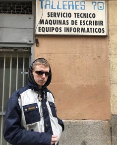 a man standing in front of a tall building with a sign on it's side