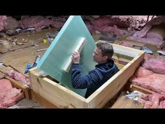 a man is holding up a piece of wood in a box that's filled with pink rocks