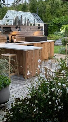 an outdoor kitchen is surrounded by plants and flowers