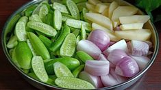 several different types of vegetables are in a bowl on a wooden table, including onions and celery