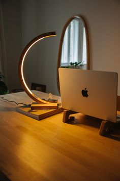 an apple computer sitting on top of a wooden desk next to a mirror and lamp