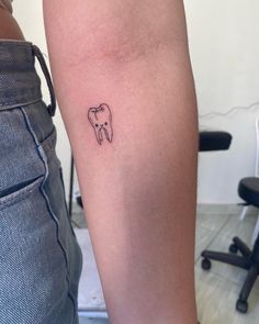 a small tooth tattoo on the arm