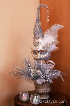 a silver and white mask on top of a wooden table next to a candle holder