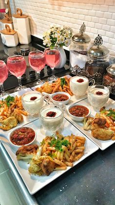 a table topped with lots of different types of food and glasses of wine next to each other