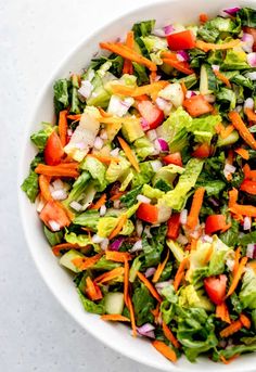 a salad with carrots, celery and onions in a white bowl on a table