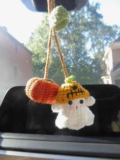 a crocheted hat hanging from the side of a car window with two strings attached to it