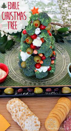 a platter with cheese, crackers and broccoli on it next to other food items